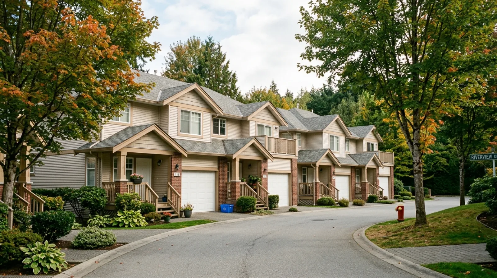 A row of 1990s two-storey townhomes in Citadel Port Coquitlam with attached garages and a quiet internal driveway