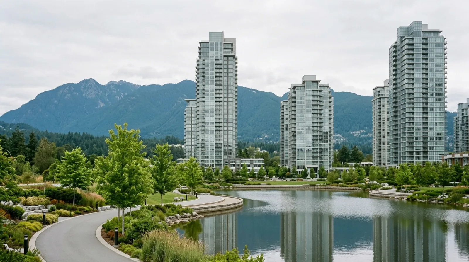 Apartment towers around a landscaped lake with a park path and mountains behind them