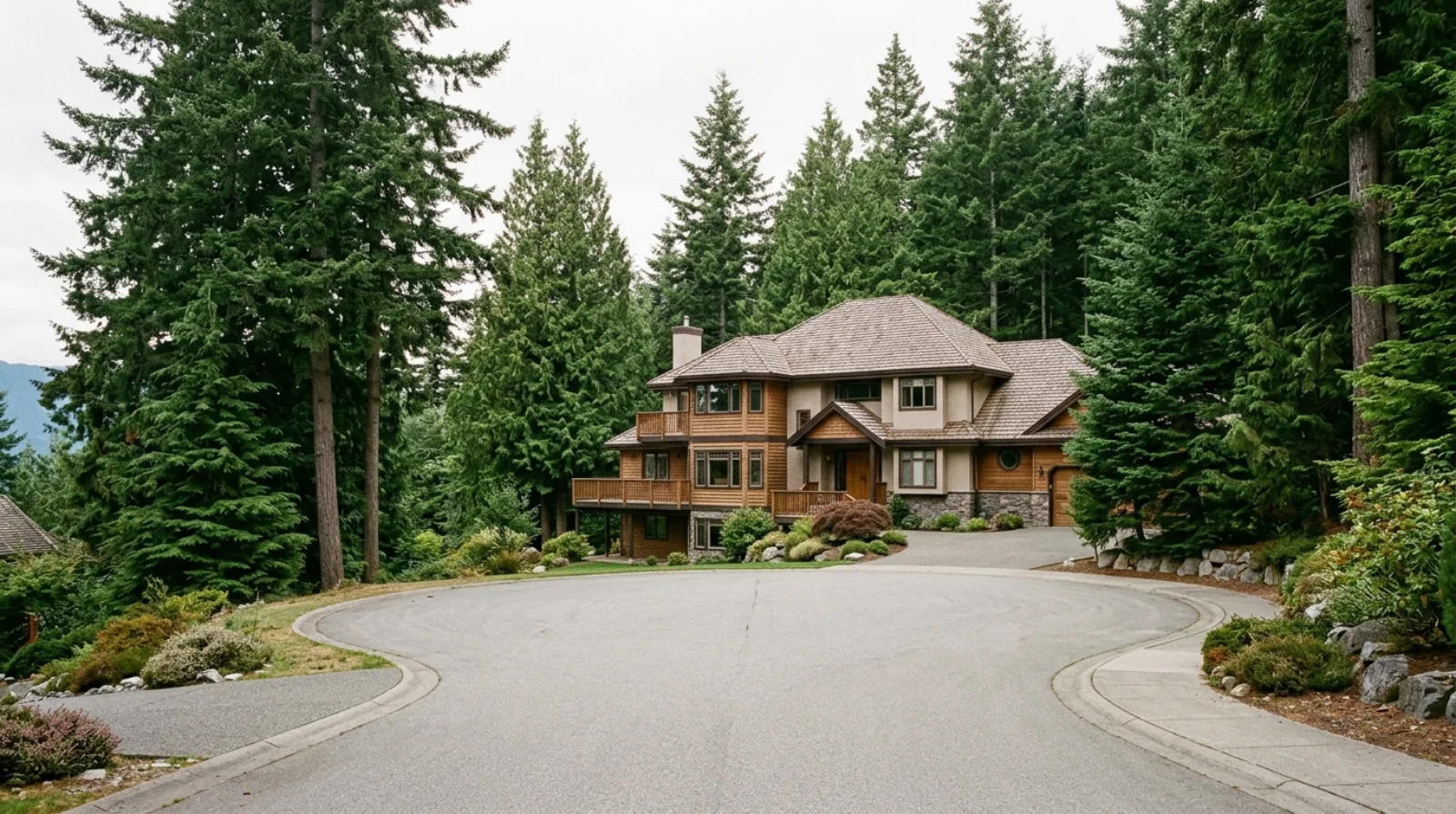 A large 1980s house on a hillside cul-de-sac surrounded by tall evergreens